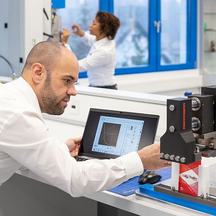 Employee_checks_sealing_result_packaging_1000x1000px Herrmann Ultraschall employee checks the sealing result for packaging